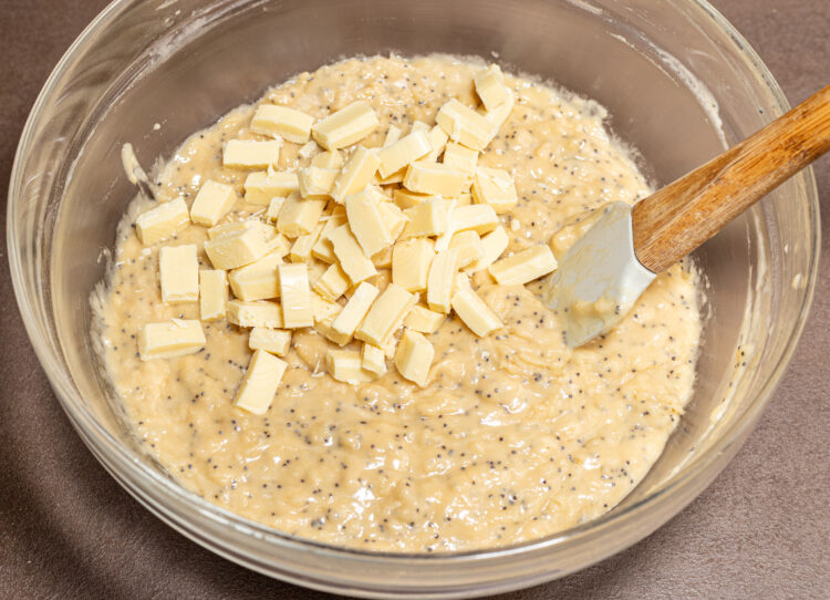 Chopped chocolate added to a bowl with poppy seed batter.