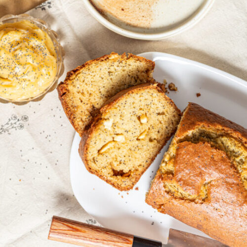 White chocolate poppy seed loaf cake sliced with honey butter on the side.