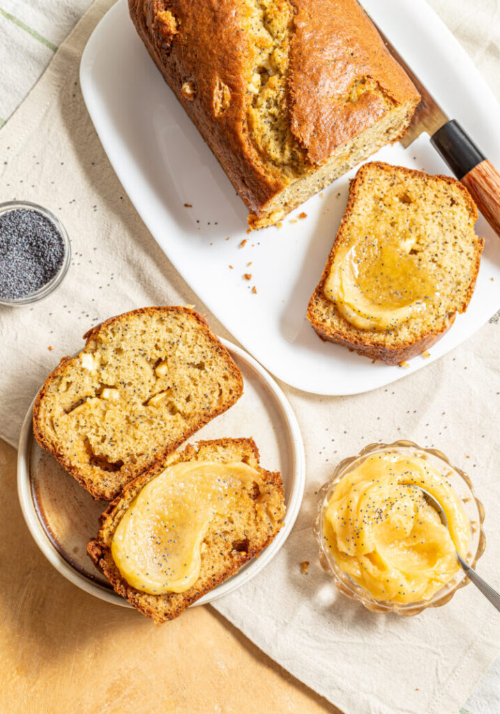 Sliced white chocolate poppy seed loaf cake with honey butter spread on top.