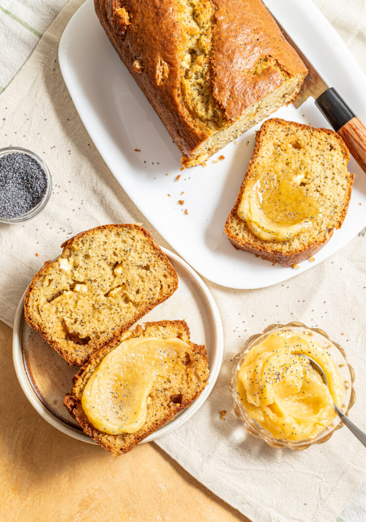 Sliced white chocolate poppy seed loaf cake with honey butter spread on top.