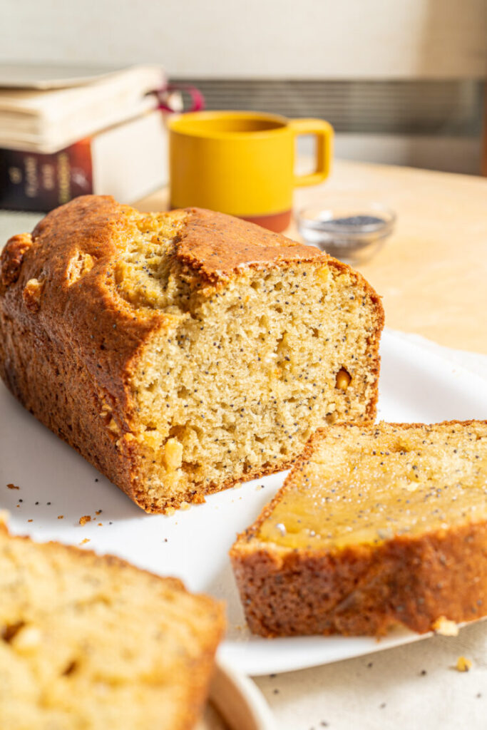 Sliced white chocolate poppy seed loaf cake on a plate.