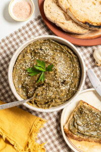 Roasted veggie spread in a bowl with a side of bread.