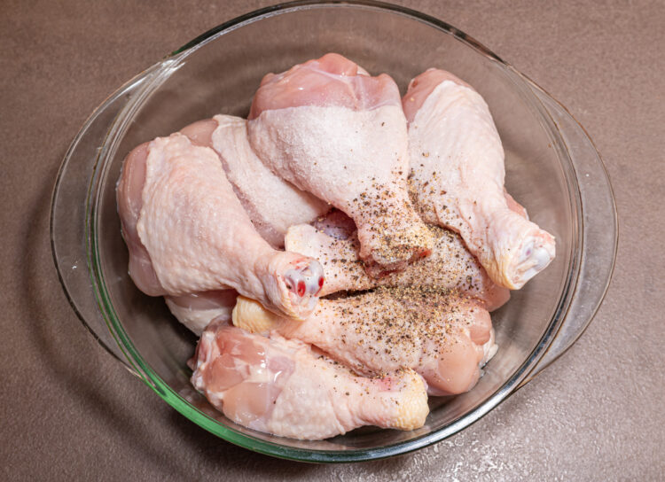 Chicken drumsticks seasoned in a bowl.