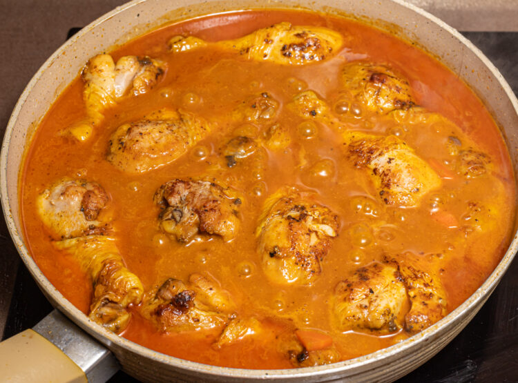 Cooking chicken coconut curry in a skillet.