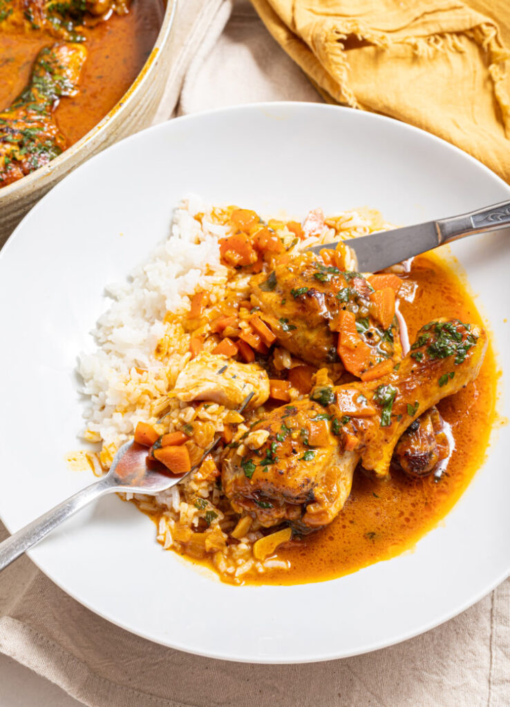 Chicken coconut curry with rice on a plate with a fork and a knife.