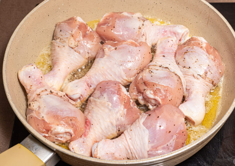 Cooking chicken drumsticks in a skillet.