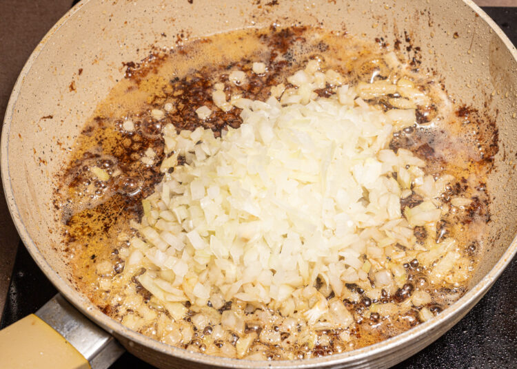 Chopped onion added to a skillet with melted butter.