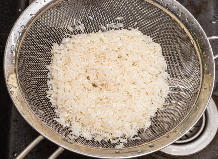 Rice in a sieve over a sink.