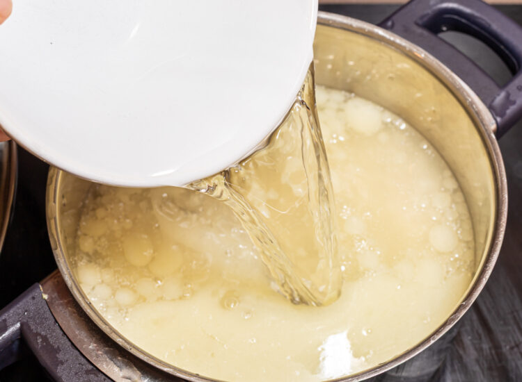 Adding water to a pot with liquid.