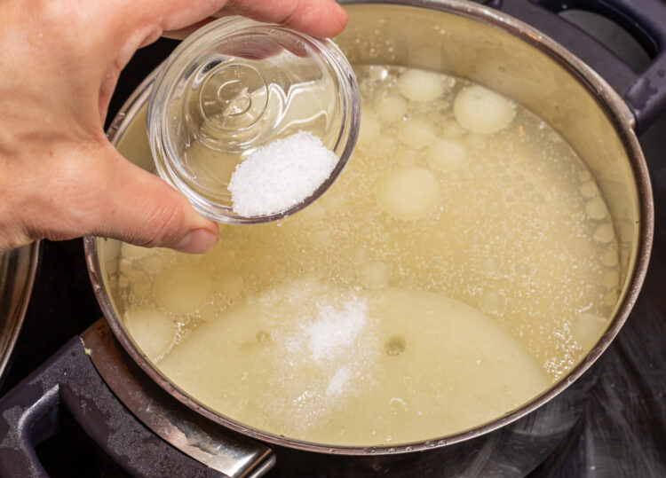 Adding salt to a pot with stock.
